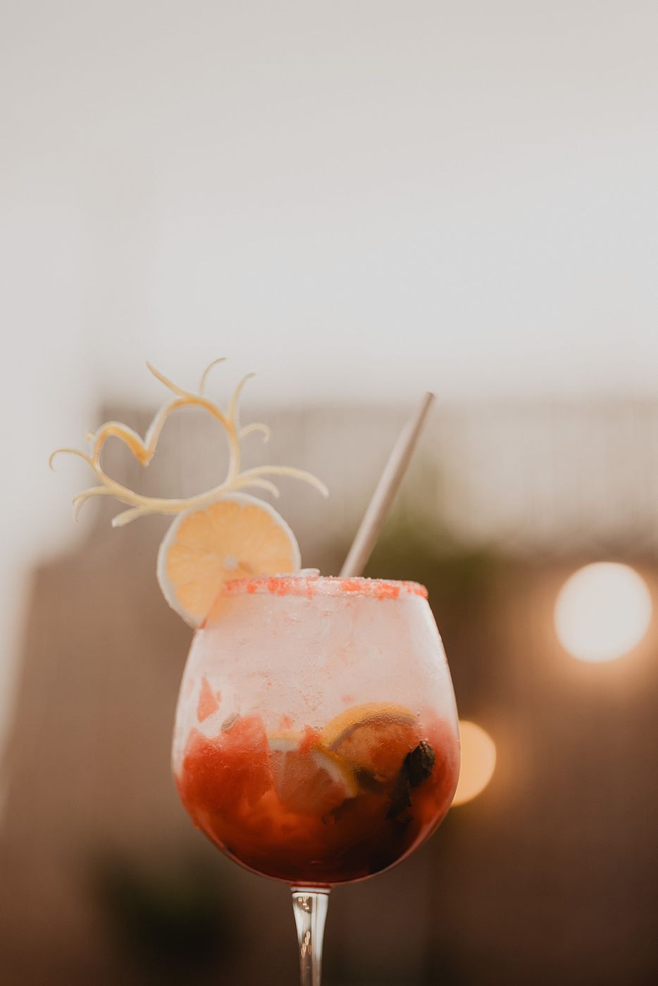 Red fruit cocktail with citrus, soft lights behind